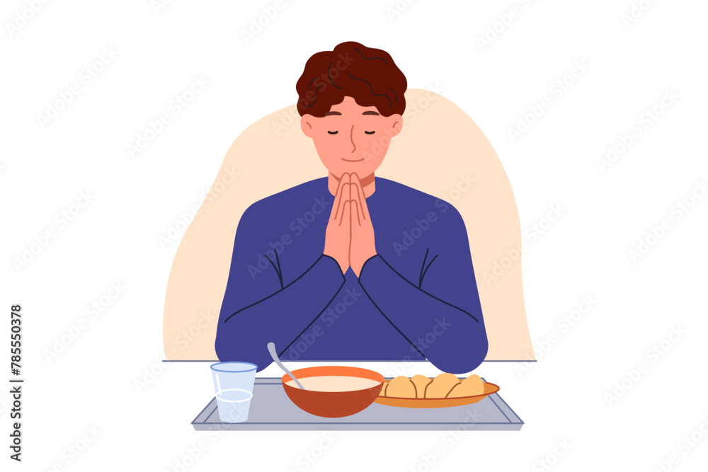 Man prays sitting at table with food, observing christian tradition and expressing gratitude to god. Guy prays with eyes closed and palms folded in front of chest, rejoicing at having money for food Man prays sitting at table with food, observing christian tradition and expressing gratitude to god. Guy prays with eyes closed and palms folded in front of chest, rejoicing at having money for food