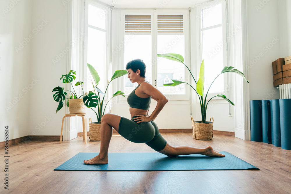 Beautiful sporty girl making yoga training in the gym studio. Young woman coach with short hair performing yoga and acroyoga poses, warming up for the class. Concepts of healthy lifestyle and sport Beautiful sporty girl making yoga training in the gym studio. Young woman coach with short hair performing yoga and acroyoga poses, warming up for the class. Concepts of healthy lifestyle and sport