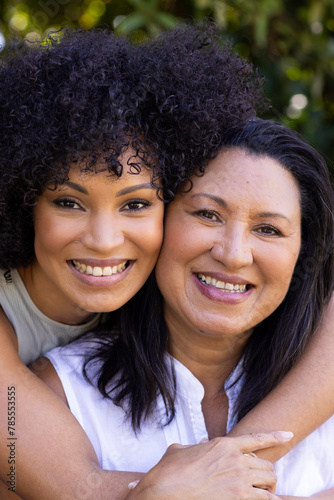 Biracial mother and daughter are hugging, smiling at home in the garden