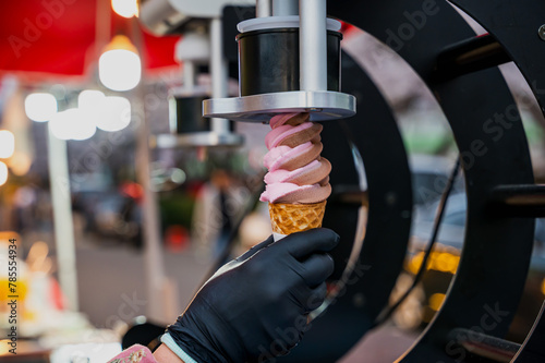 Close up hand holding twist ice cream cone on ice cream making machine 