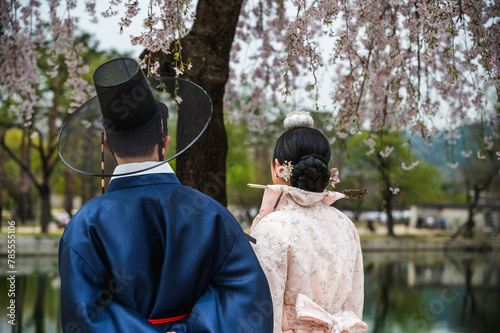 Foto Back view man and woman in Hanbok traditional Korean costume with cherry blossom