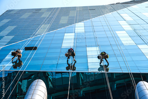 Group of high rise workers hanging on access rope cleaning highrise glass building in Seoul, South Korea photo