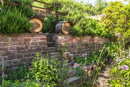 Natural garden with native plants, stone wall and insect hotels, bug hotels, insect houses. Natural gardening concept.