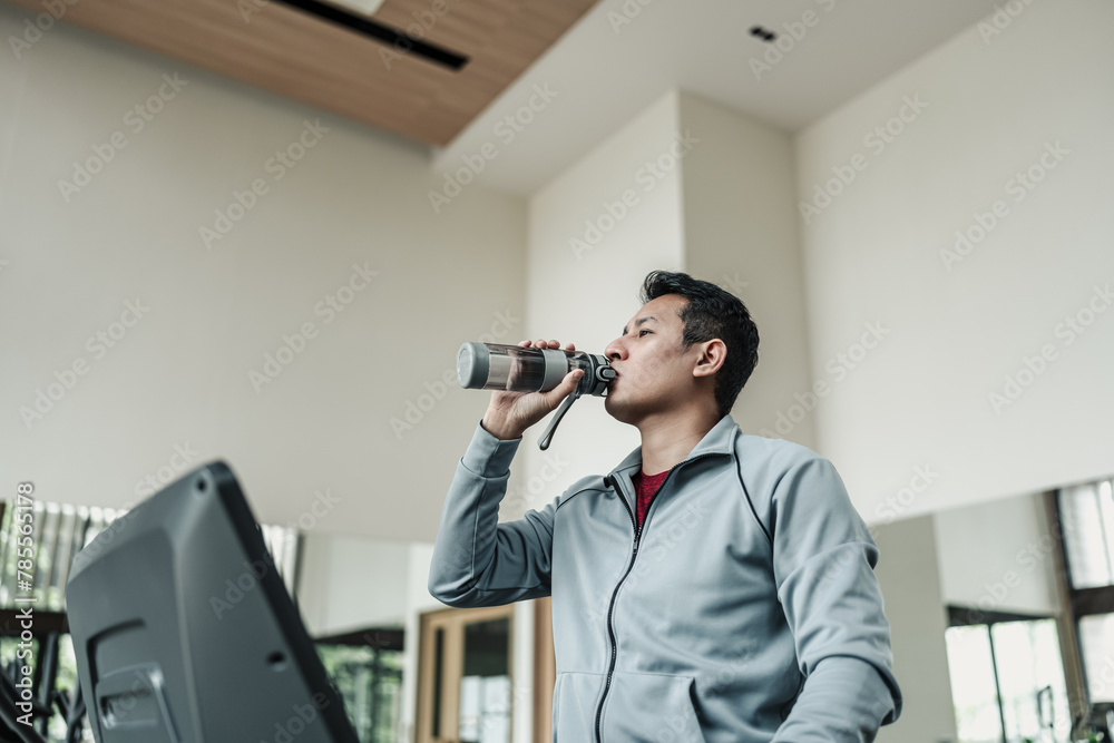 A man drinking water on treadmill in gym. Fitness, gym, workout and lifestyle concept. A man drinking water on treadmill in gym. Fitness, gym, workout and lifestyle concept.