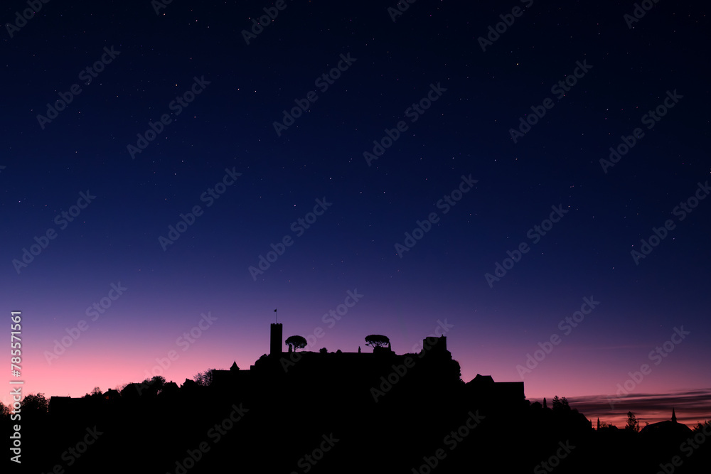 Dawn breaking over the silhouette of the medieval village of Turenne in the Correze department of France with stars overhead