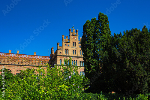Chernivtsi National University, Residence of Bukovinian and Dalmatian Metropolitans in the city of Chernivtsi, Ukraine. Red brick facade with green trees and bushes at sunny day. UNESCO photo