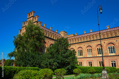 Chernivtsi National University, Residence of Bukovinian and Dalmatian Metropolitans in the city of Chernivtsi, Ukraine. Red brick facade with green trees and bushes at sunny day