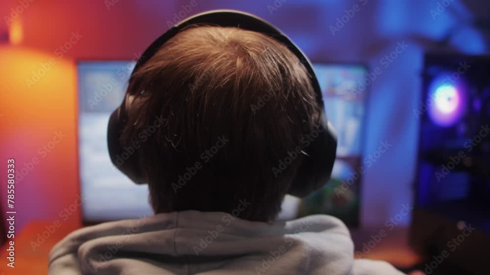 Young man has a video game stream or podcast in neon room. Male gamer playing online video games on his personal computer. Young man has a video game stream or podcast in neon room. Male gamer playing online video games on his personal computer.