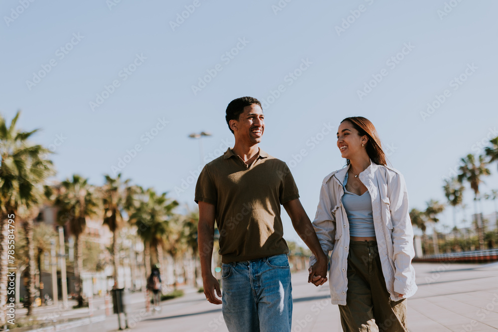 Young couple enjoying a sunny stroll along Barcelona palm-lined promenade Young couple enjoying a sunny stroll along Barcelona palm-lined promenade
