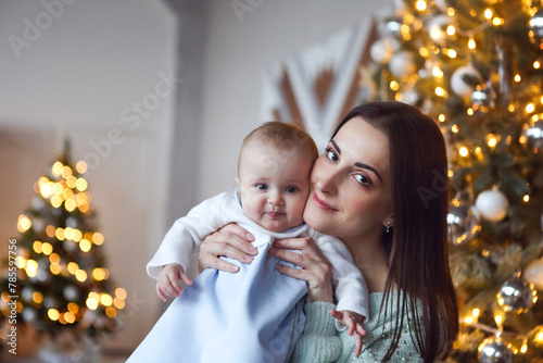 Beautiful happy mother with lher ittle daughter in knit sweater sitting on the background of Christmas interior photo