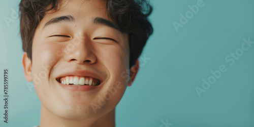 Portrait of a happy South Korean man on a blue background and smiling at the camera photo