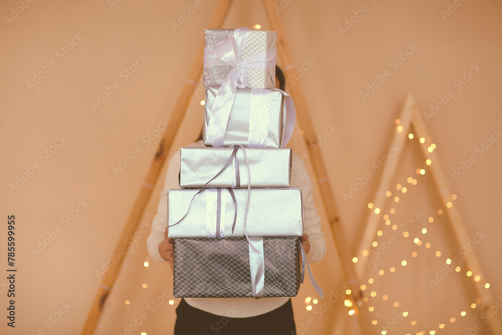Woman holding wrapped gifts covering face Woman holding wrapped gifts covering face