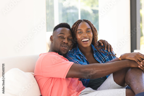 African American couple sitting close, smiling at camera at home photo