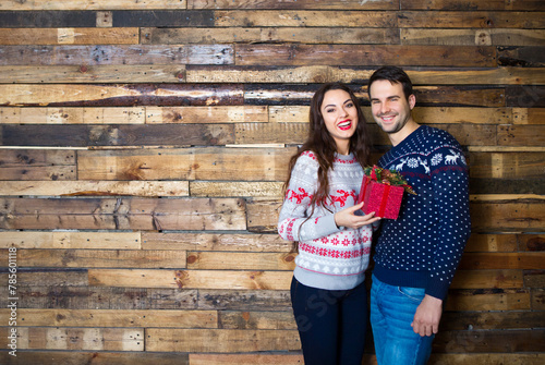 Young couple near wooden wall celebrating Christmas