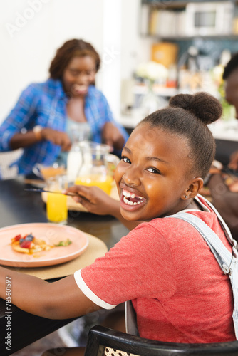 African American family enjoying breakfast at home, young girl smiling at camera