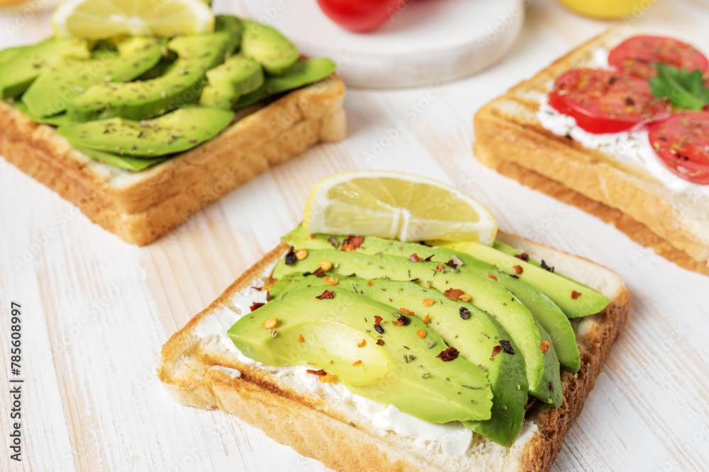 Sliced avocado on toast bread with spices on white wooden background. Food concept. Sliced avocado on toast bread with spices on white wooden background. Food concept.