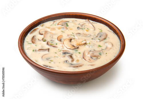 Cream of mushroom soup in terracotta clay bowl isolated on white background.