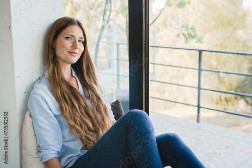 Dreamy young woman sitting by the window thinking about future events at home alone. Beautiful girl female lady dreaming , making plans, creating new ideas