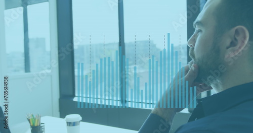 Image of financial graphs and data over caucasian man using computer in office