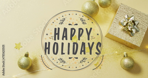Image of happy holidays text over christmas decorations on yellow background