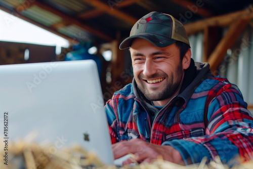 Farmer enjoys a light moment on his laptop, blending rural living with modern technology.