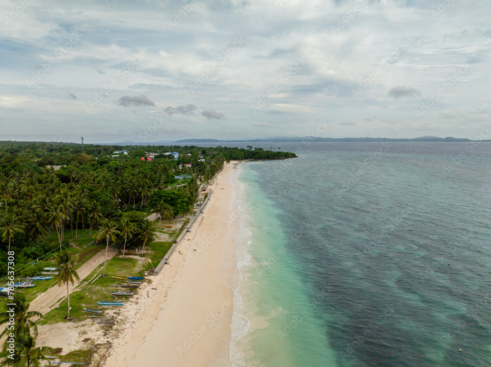 Poblacion San Jose and white sandy beach with ocean waves in Carabao Island. Romblon. Philippines.