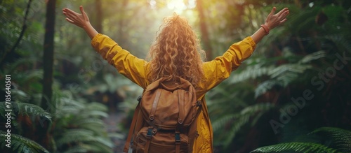 Young woman arms raised enjoying the fresh air in green forest.