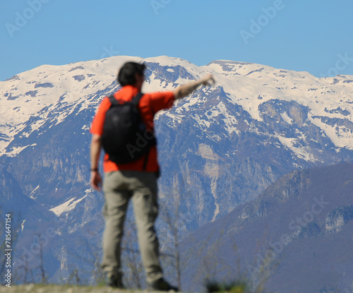 male hiker pointing at snowcapped mountains with backpack on during high altitude hike