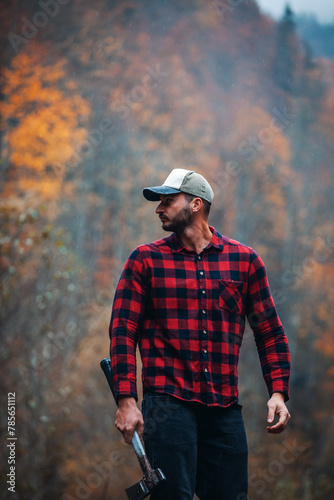 Handsome Lumberjack in Red Checkered Shirt with Axe in Autumn Foggy Forest