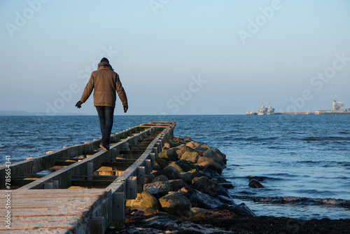 Mann balanciert auf Steg im Winter.
