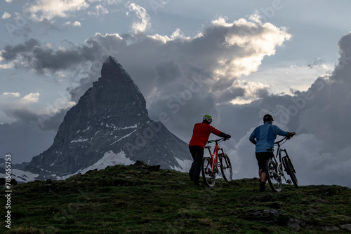 Silhouetted bikers against mountain at summer dusk photo