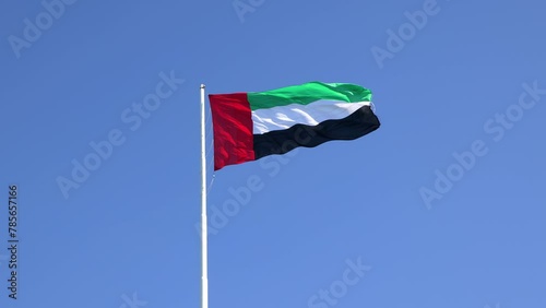 UAE flag waving in the blue sky, national symbol of UAE