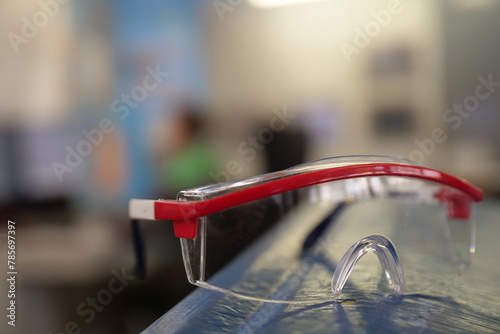 Protective goggles or safety glasses. Protective clothing to protect the eyes of a person. Single object against a blurred industrial background.