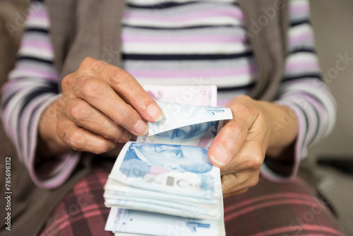 Closeup of wrinkled hands holding turkish lira banknotes   photo