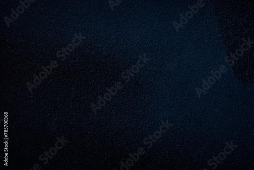 Macro close-up of a dark wall spray painted with black and dark blue. Abstract full frame textured grunge graffiti background with copy space.