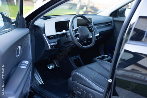 Steering wheel of a electric vehicle, interior cockpit, electric buttons, digital speedometer, front seats, textile, windows, console, gear shift. Car dashboard with a digital touchscreen photo