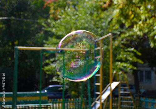 a large soap bubble shimmers in different colors and sparkles in the rays of the bright sun. entertainment for children