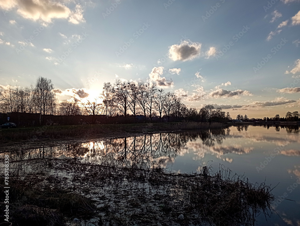 Spring landscape: trees reflected in the lake on a spring evening Spring landscape: trees reflected in the lake on a spring evening