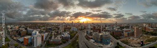 A beautiful drone photograph of Leeds, West Yorkshire showcasing the sprawling city centre at sunrise with ongoing construction projects and the majesty of building silhouettes