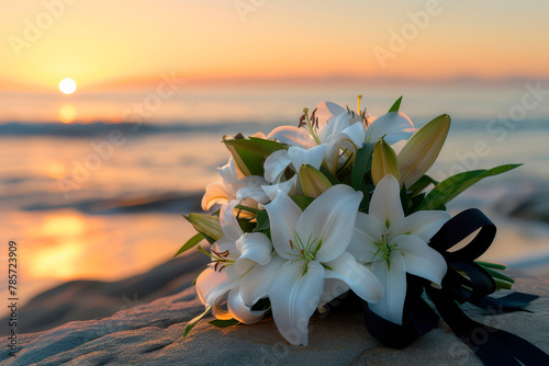 Black funeral ribbon and white lily flowers on a rock by the calm sea