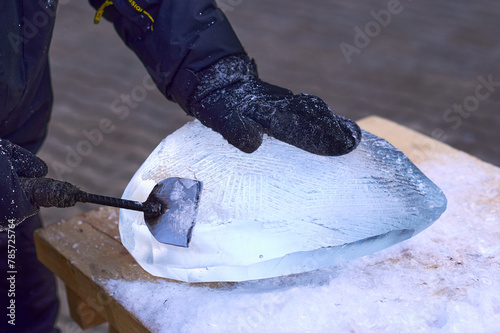 A sculptor carves a heart shape from ice using a homemade hand tool - a chisel. Valentine's day concept. Entertainment and hobbies of creative people.