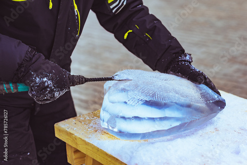 A sculptor carves a heart shape from ice using a homemade hand tool - a chisel. 