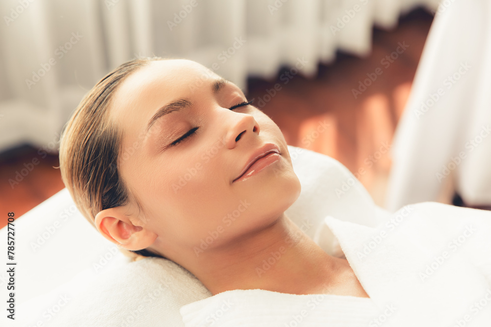 Naklejka premium Caucasian woman customer enjoying relaxing anti-stress spa massage and pampering with beauty skin recreation leisure in day light ambient salon spa at luxury resort or hotel. Quiescent