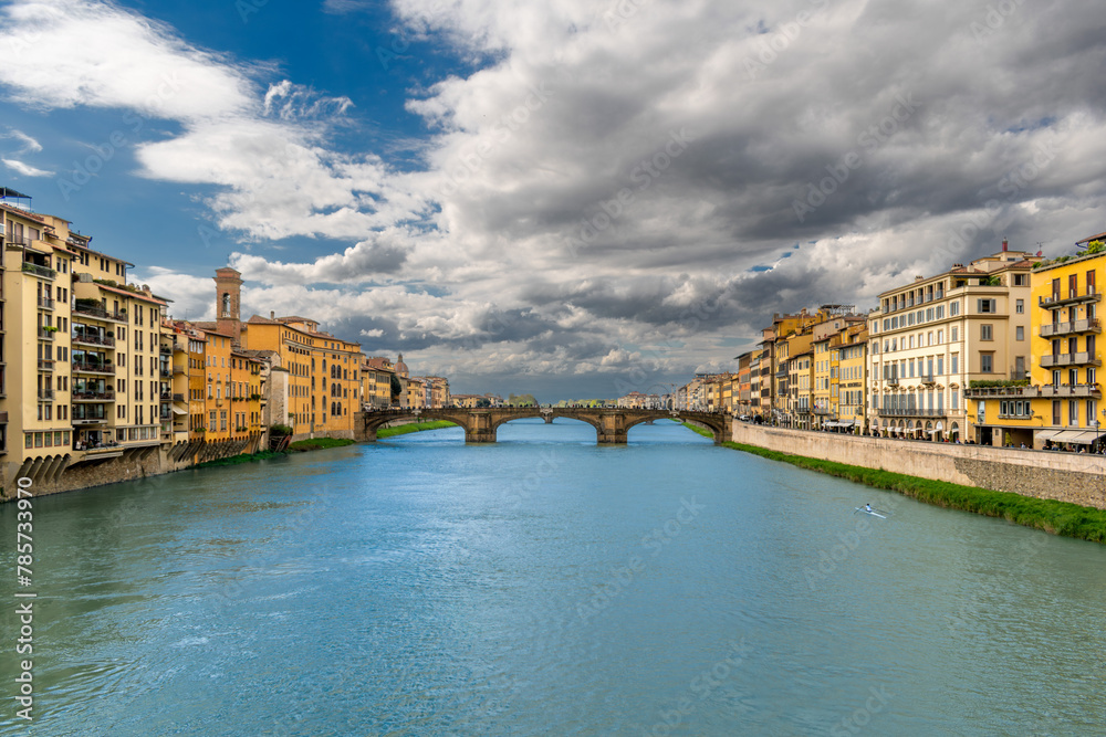 River Arno flows through the historic center of Florence, Italy, among ancient palaces with Santa Trinita arch bridge