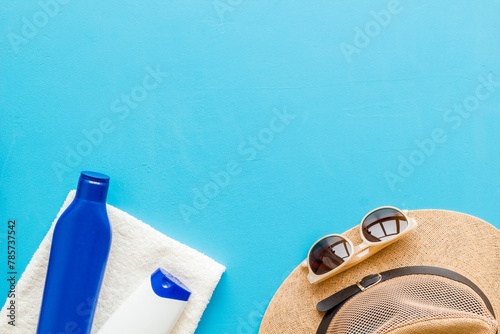 Summer holiday beach background. Male straw hat with sunscreen and sunglasses, top view
