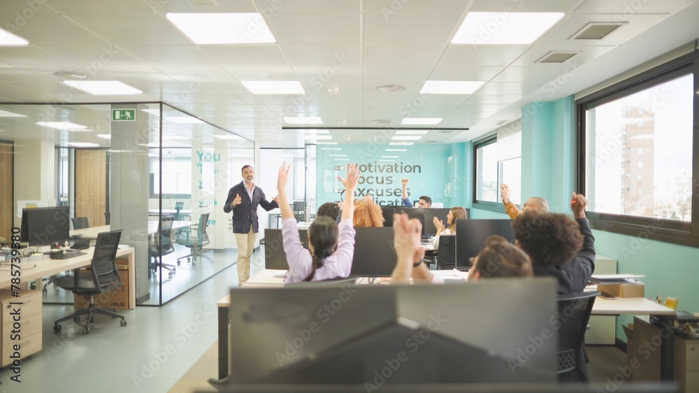 Boss sharing good news with celebrating employees in a bright motivational office settin