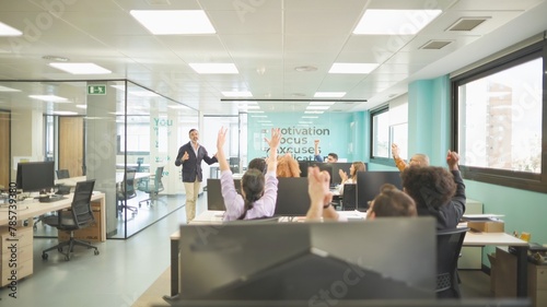 Boss sharing good news with celebrating employees in a bright motivational office settin