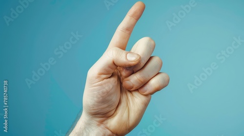 Close-Up of a Human Hand Making the ‘Fingers Crossed’ Gesture Against a Vibrant Blue Background, Symbolizing Hope and Good Luck photo