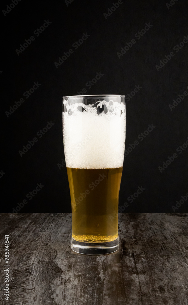 A glass of craft light beer on a dark background. The concept of brewing.
