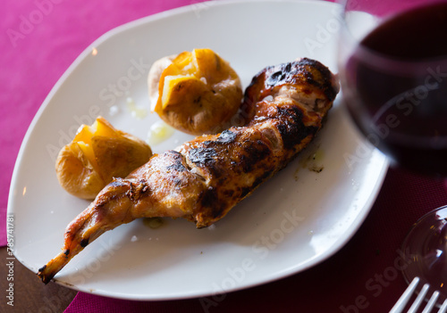 Picture of tasty baked quarter of rabbit, served with pototoes at plate photo